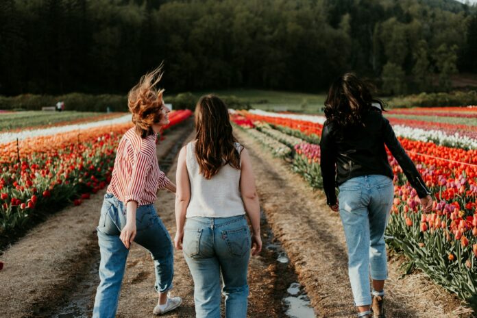 Photo by Priscilla Du Preez 🇨🇦 thee women walking between orange flower field