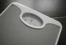 다이어트와 운동: 건강을 위한 동반자로서의 역할 a bathroom scale sitting on top of a wooden table