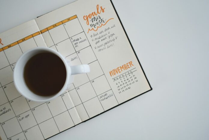 Photo by Estée Janssens white ceramic mug with coffee on top of a planner