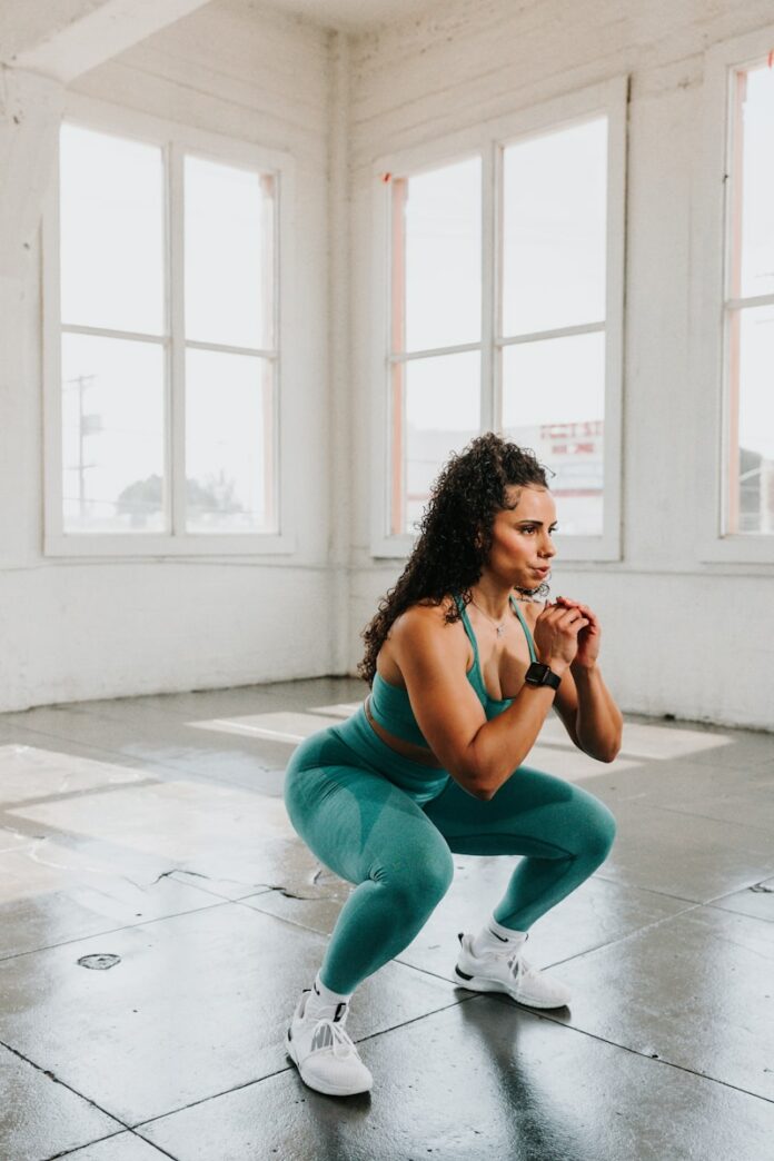 Photo by SUNDAY II SUNDAY a woman squatting on the floor in a gym