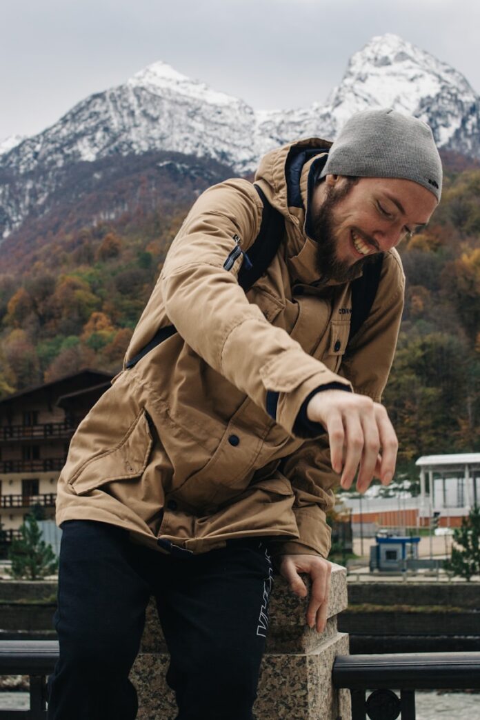 Photo by Olga Nayda man sitting on railings behind snow capped mountain