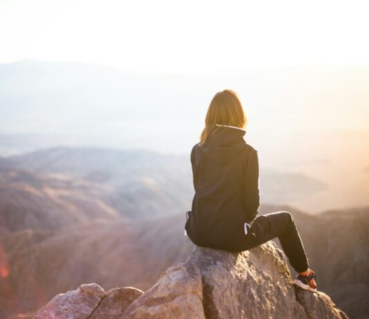심리적 안정을 위한 운동의 역할 person sitting on top of gray rock overlooking mountain during daytime