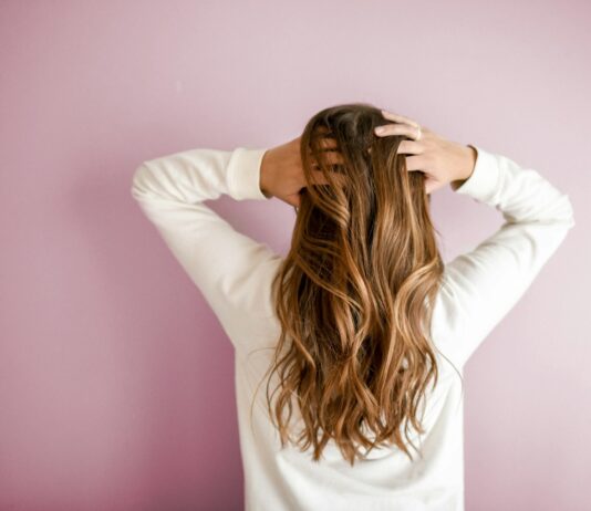 “요즘 머리카락이 많이 빠져요”… 탈모보다 먼저 챙겨야 할 것 woman in white long-sleeved shirt standing in front of pink wall