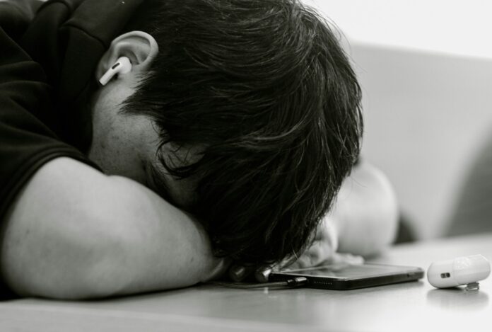 A man laying his head on his cell phone