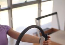 필라테스, 몸과 마음을 깨우는 건강한 움직임의 시작 a woman sitting on the floor holding a steering wheel