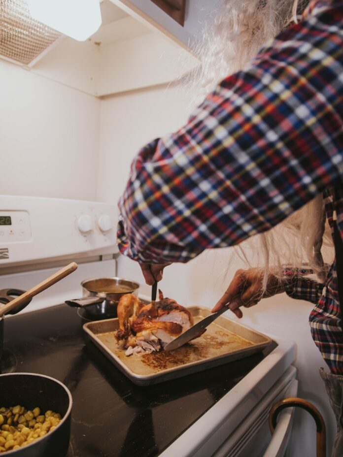 Photo by Gio Bartlett a person cutting a turkey on a cutting board