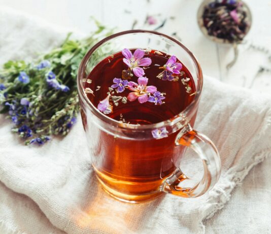 일상으로 스며든 대체요법, 건강한 삶 위한 작은 변화 a glass mug filled with tea next to a bunch of flowers