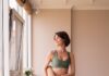 “필라테스, 바쁜 현대인의 새로운 일상 루틴으로 자리잡다” a woman in a green sports bra top and leggings holding a yoga mat